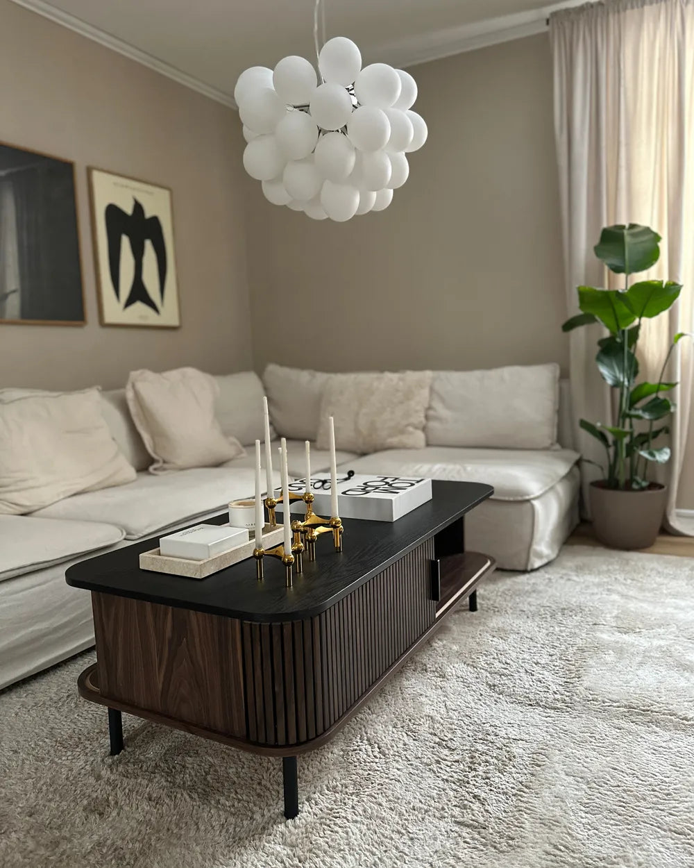 The JOSE dark brown coffee table is a rectangular coffee table with built-in storage, designed for modern living rooms. It features sliding doors that provide easy access to concealed storage compartments, as well as two open shelves for everyday items.